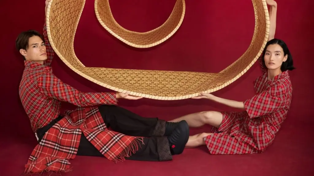 Burberry campaign with models in red plaid holding a woven serpentine structure for Lunar New Year 2025.