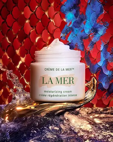 La Mer cream jar against blue and red snake-skin inspired background with water textures.
