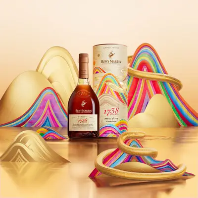 Rémy Martin bottle and packaging with golden snake design and colorful artistic waves for 2025 Lunar New Year.
