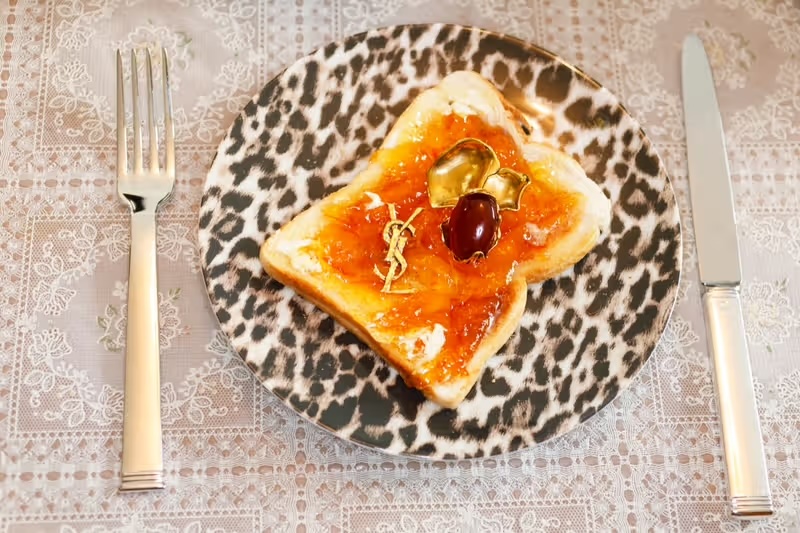 Food imagery in marketing showing toast with jam and gold accents on patterned plate