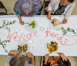 People from different cultural backgrounds sharing a meal together, representing multicultural marketing and cultural connection.
