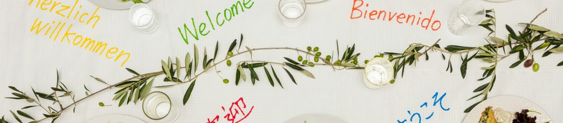 Multicultural dinner table with welcome messages in different languages illustrating multicultural marketing and cultural diversity.