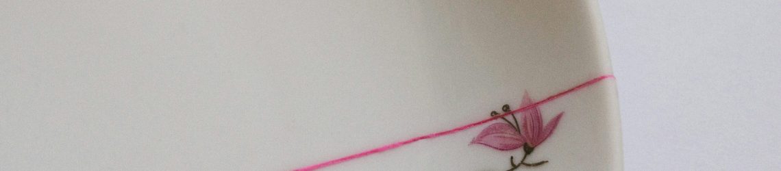 White ceramic plate repaired with a bright pink line, symbolising Kintsugi and the Wabi Sabi philosophy of imperfect beauty.