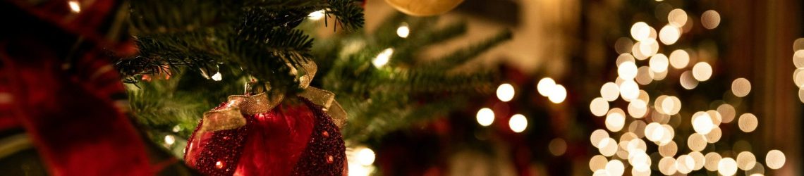 Close-up of a Christmas tree with red ornaments and warm lights, illustrating Christmas 2025 graphic codes in festive decor.